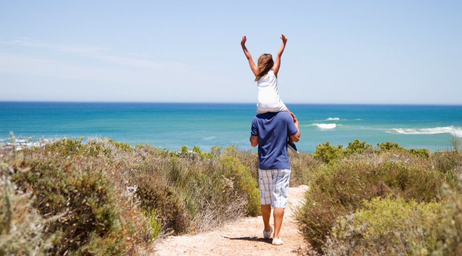 father and daughter walking toward beach