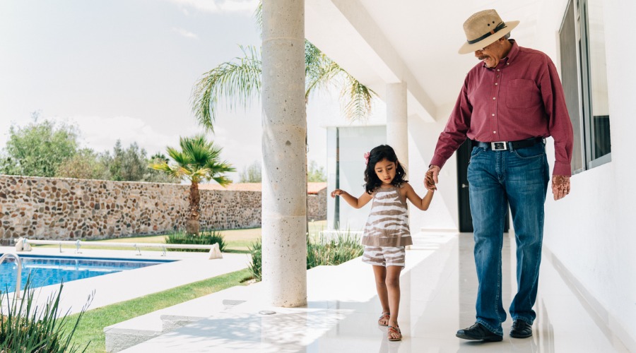 grandfather and granddaughter walking near pool