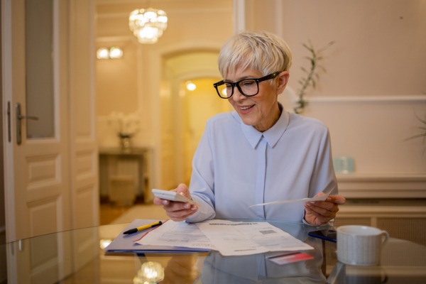 mature woman looking at paperwork holding calculator